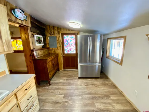 a view of a refrigerator in kitchen and dining room with wooden floor