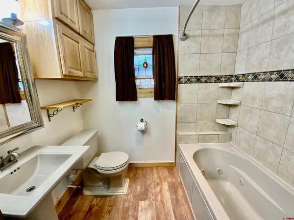 a bedroom with a bed and dresser with wooden floor