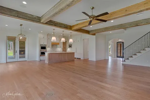 a view of a livingroom with a ceiling fan wooden floor and a ceiling fan