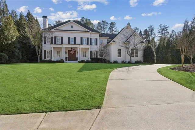 a view of a big house with a big yard and large trees