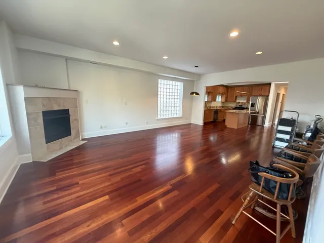 a view of an empty room with wooden floor fireplace and windows