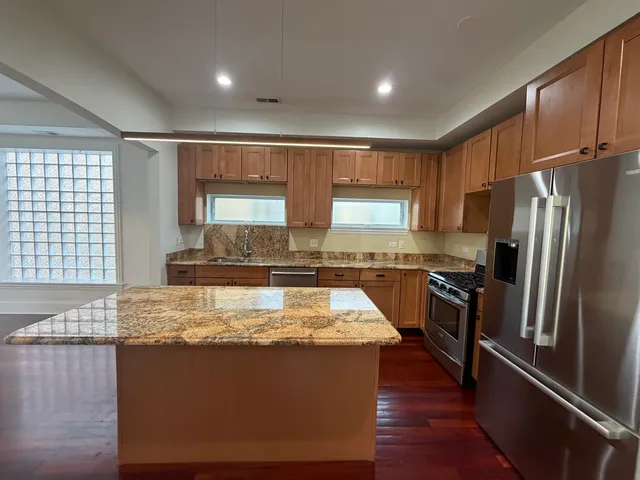 a kitchen with granite countertop a refrigerator and a stove top oven