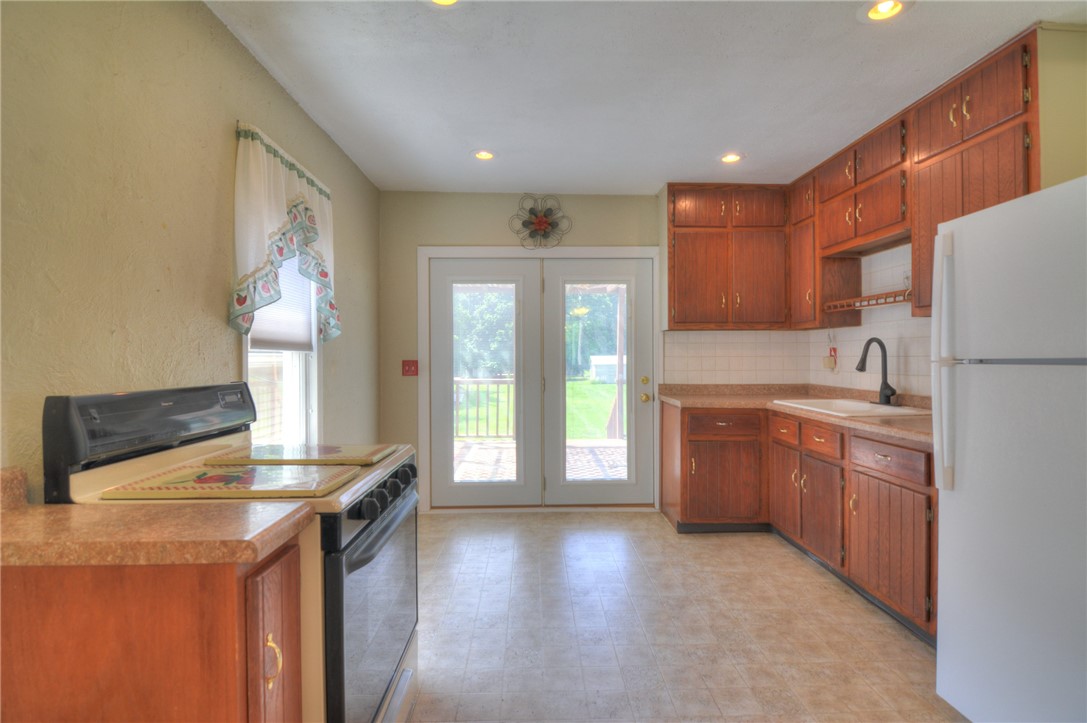 63 Grays Lane Decatur, IL 62526 - Photo 11 of 28 a kitchen with granite countertop a refrigerator a sink a stove and white cabinets