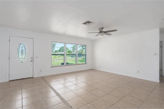 an empty room with windows and ceiling fan
