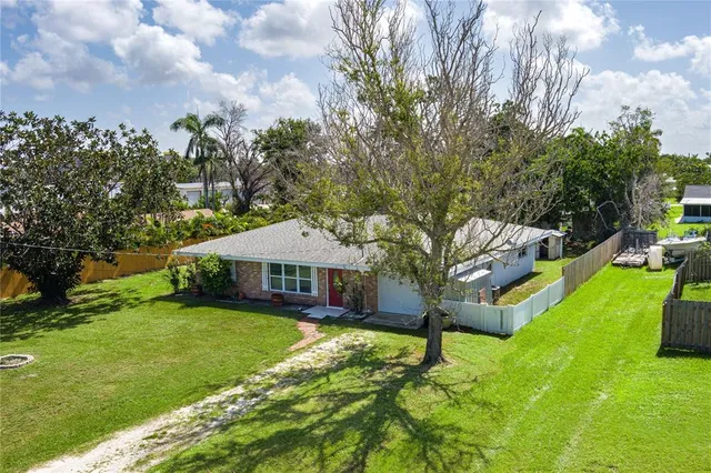 a view of a house with a big yard and large trees