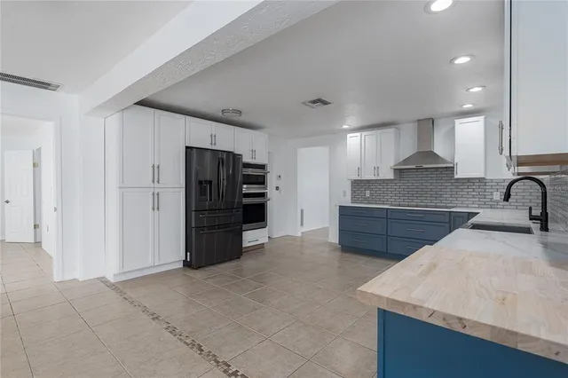 a large kitchen with stainless steel appliances kitchen island granite countertop a refrigerator and a sink