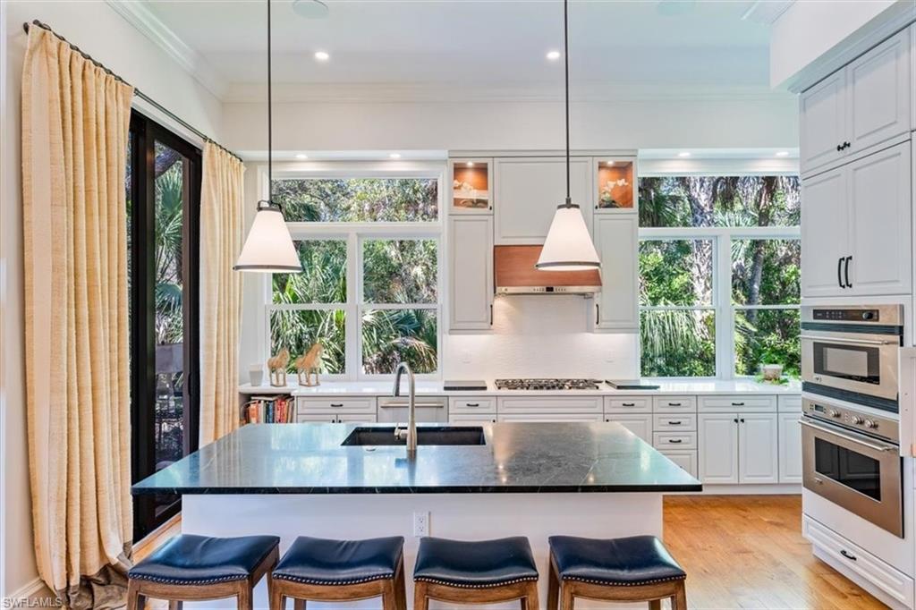 18051 Lagos Way Naples, FL 34110 - Photo 10 of 26 a kitchen with a table chairs stove and cabinets