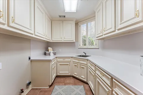 a kitchen with stainless steel appliances granite countertop a sink a stove and white cabinets with wooden floor