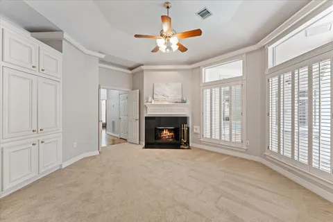 a view of a livingroom with a fireplace a ceiling fan and windows