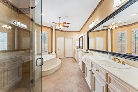 a spacious bathroom with a granite countertop double vanity sink a mirror and a bathtub