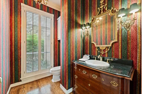 a bathroom with a granite countertop sink a toilet a mirror and shower curtain