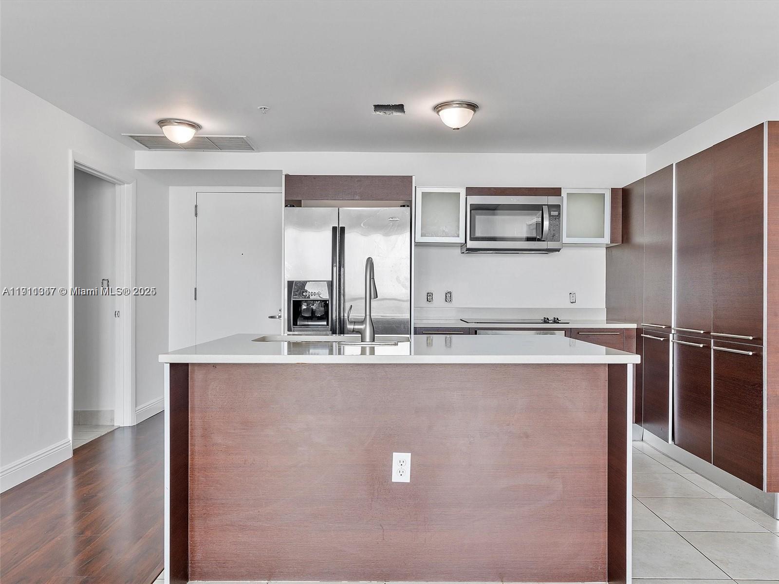 1900 North Bayshore Drive, Unit 1614 Miami, FL 33132 - Photo 4 of 15 a kitchen with kitchen island a sink a counter top space and stainless steel appliances