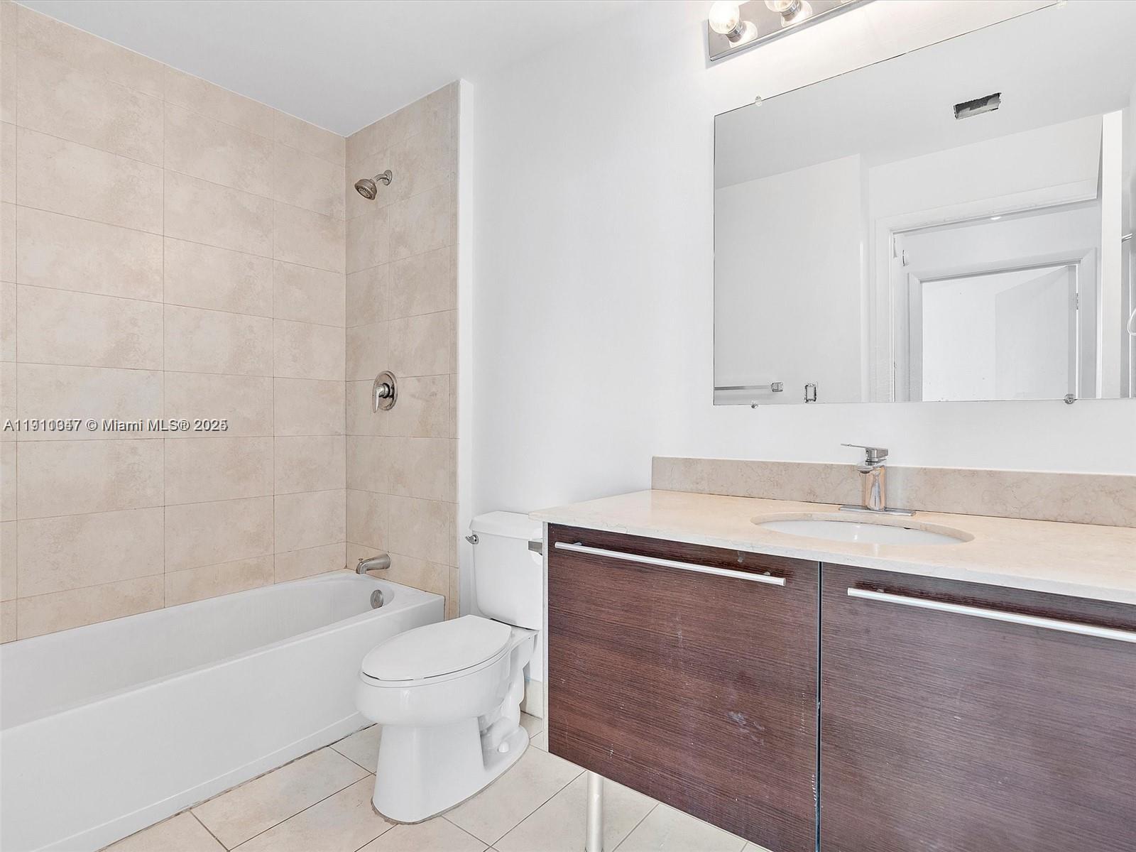 1900 North Bayshore Drive, Unit 1614 Miami, FL 33132 - Photo 8 of 15 a bathroom with a granite countertop sink toilet a mirror and bathtub