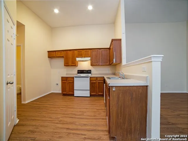 a kitchen with granite countertop a stove and a wooden floor