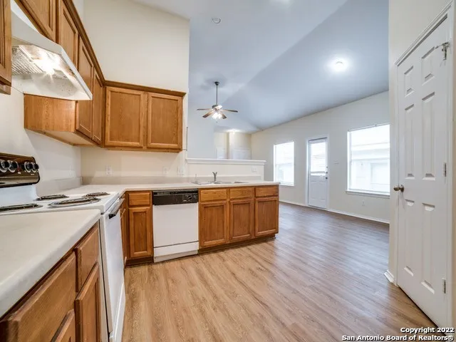 a kitchen with stainless steel appliances granite countertop wooden floors and white cabinets