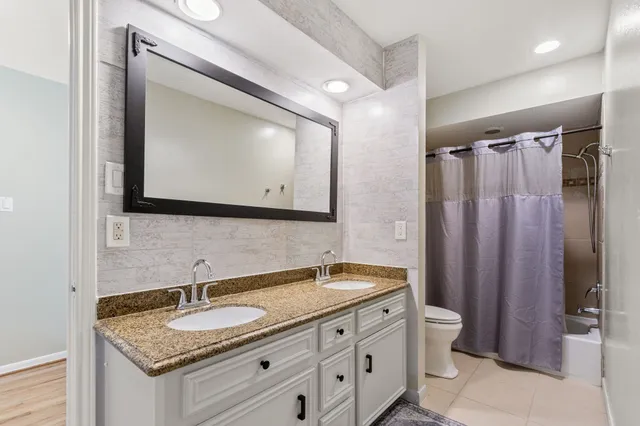 a bathroom with a granite countertop sink toilet a mirror and shower