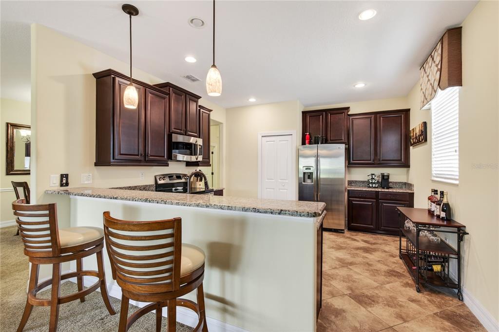 3651 Limestone Street Clermont, FL 34711 - Photo 4 of 41 a kitchen with kitchen island granite countertop wooden cabinets and a refrigerator