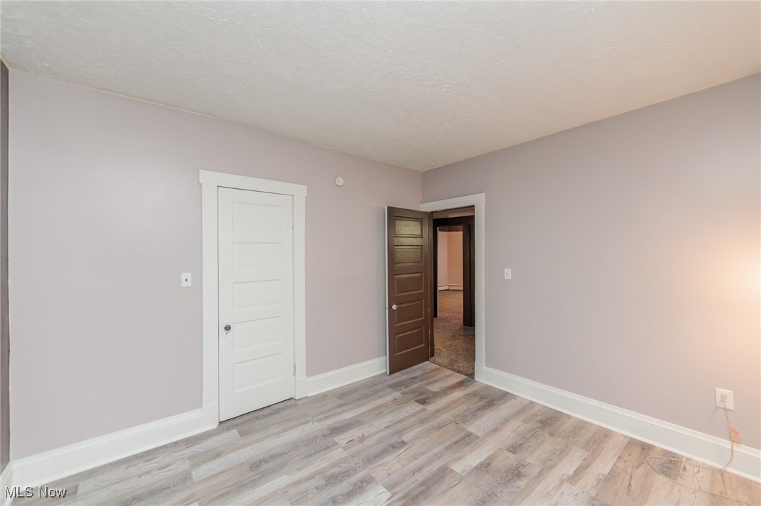 3181 Warren Road Cleveland, OH 44111 - Photo 17 of 28 Unfurnished bedroom featuring a textured ceiling, a closet, and light wood-type flooring