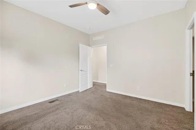 an empty room with a ceiling fan and carpet