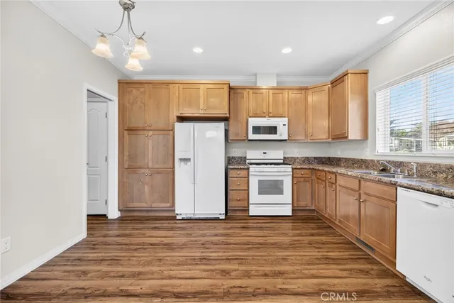 a kitchen with kitchen island granite countertop white cabinets a refrigerator a sink a stove and a microwave