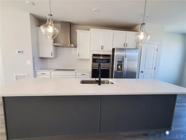 a kitchen with kitchen island a refrigerator a sink and a stove