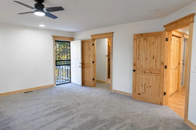 an empty room with a ceiling fan and carpet
