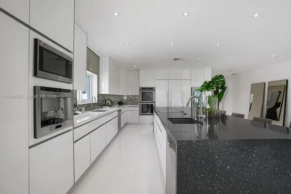 a large white kitchen with lots of counter top space appliances and cabinets