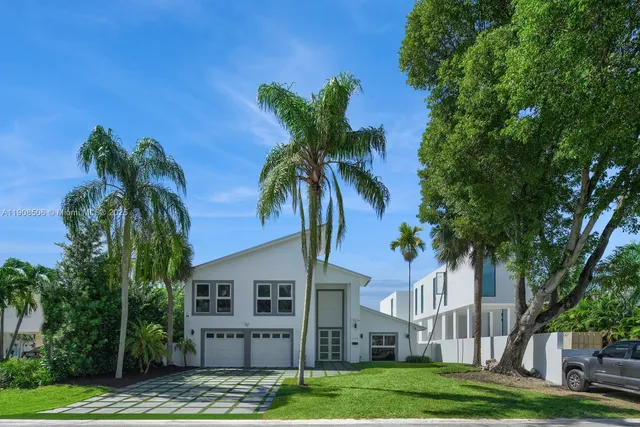 a front view of a house with a garden and trees