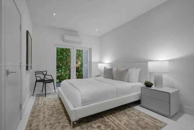 a bedroom with a bed lamp and a large window