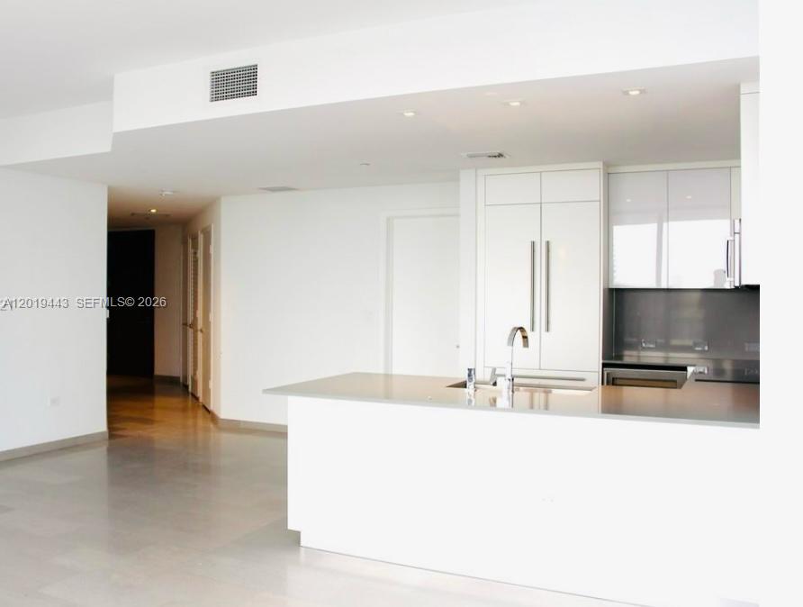 68 Southeast 6th Street, Unit 2702 Miami, FL 33131 - Photo 3 of 28 a large kitchen with kitchen island a sink stainless steel appliances and cabinets