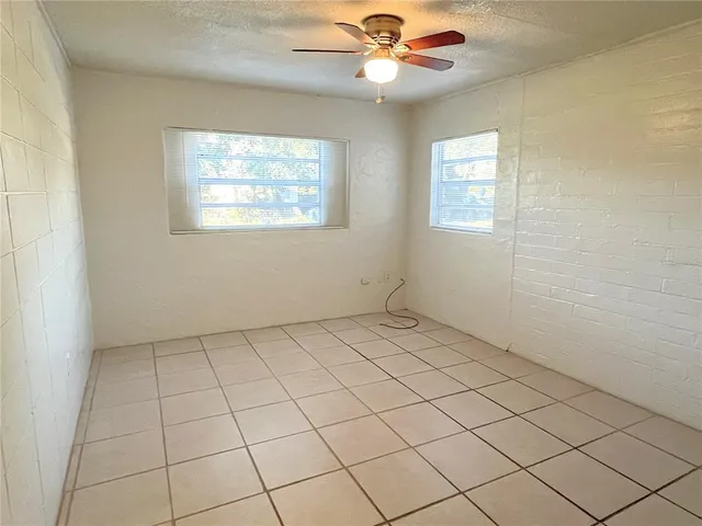 an empty room with windows and fan