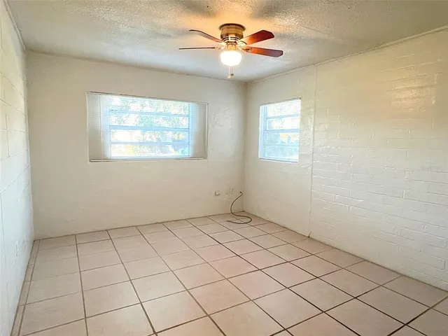 an empty room with windows and fan