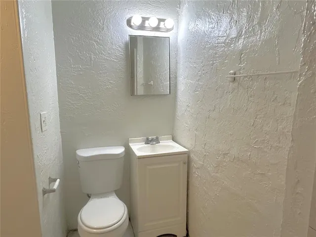 a bathroom with a toilet sink vanity and mirror