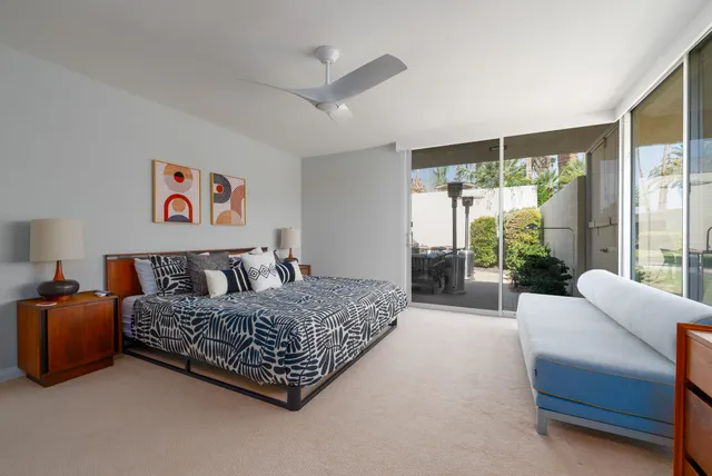 a bedroom with bed table and flat screen tv