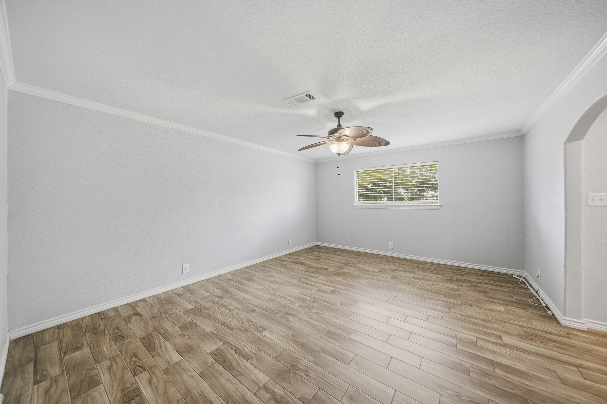 302 Country Road 893 Angleton, TX 77515 - Photo 19 of 26 Bright and spacious room with wood-like flooring, a large window, neutral gray walls, and a ceiling fan. Perfect for a living area or bedroom.