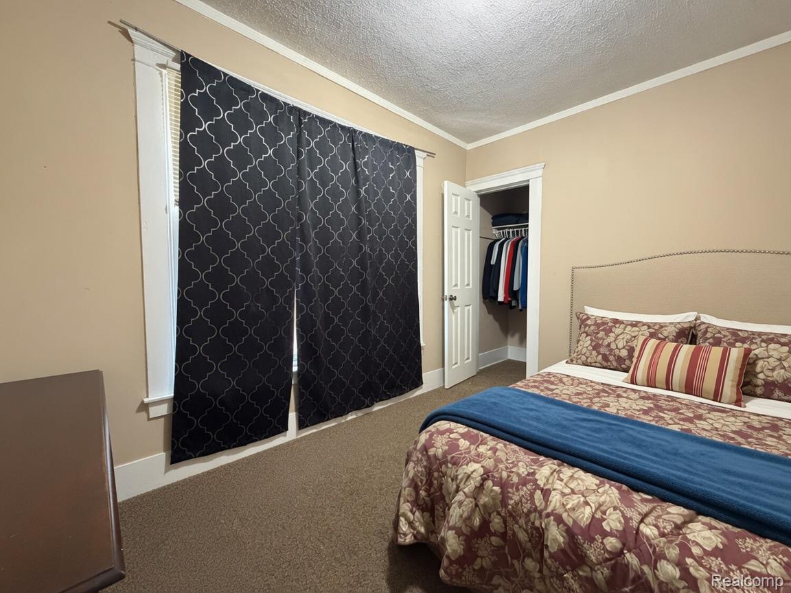 9940 Manor Detroit, MI 48204 - Photo 12 of 16 Carpeted bedroom featuring a window with blinds and patterned drapes, a closet with a bi-fold door and built-in hanging rod, and a neutral-toned wall paint