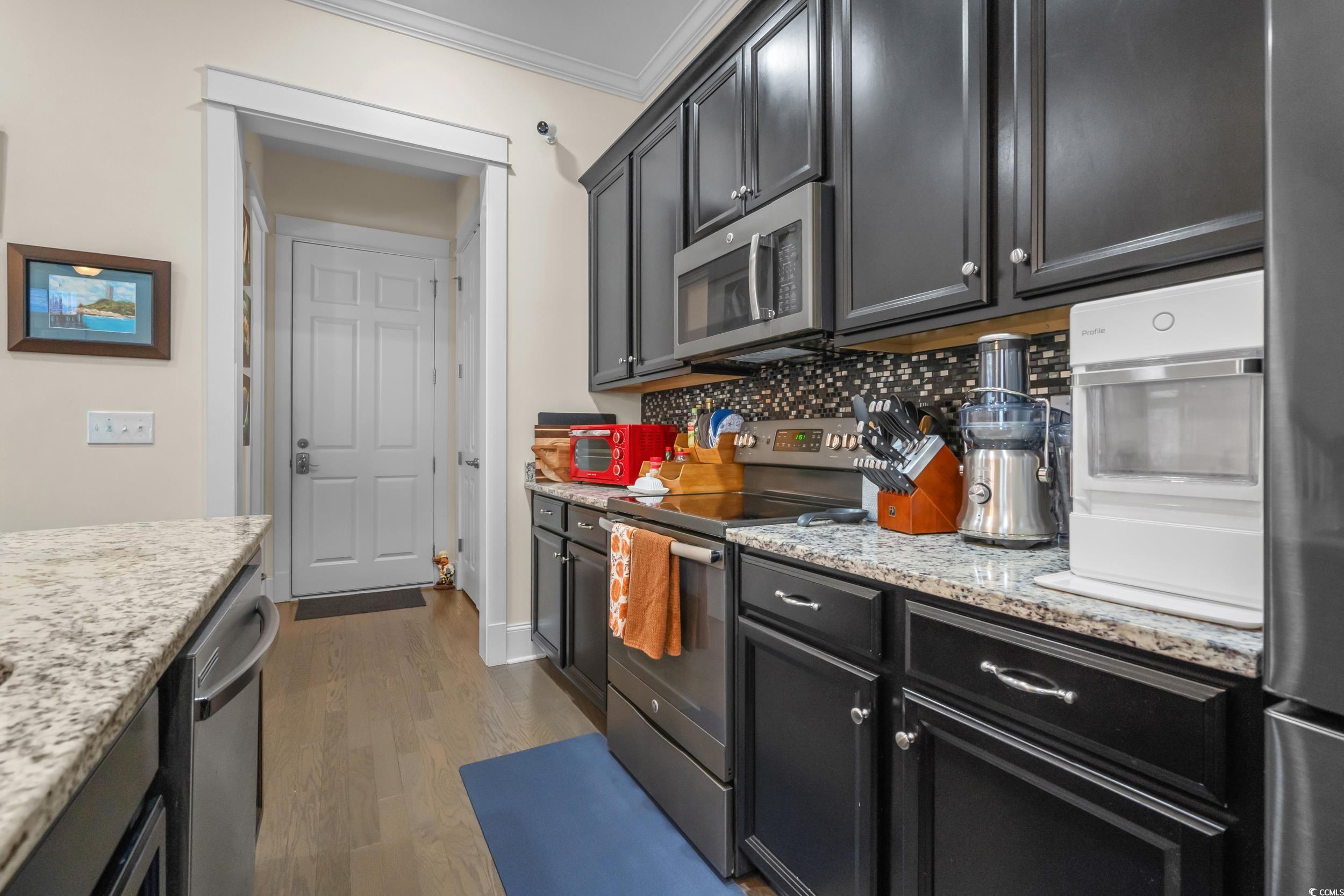 2794E Howard Avenue, Unit A Myrtle Beach, SC 29577 - Photo 13 of 40 Kitchen featuring dark cabinets, stainless steel appliances, dark wood-style floors, ornamental molding, and light stone countertops