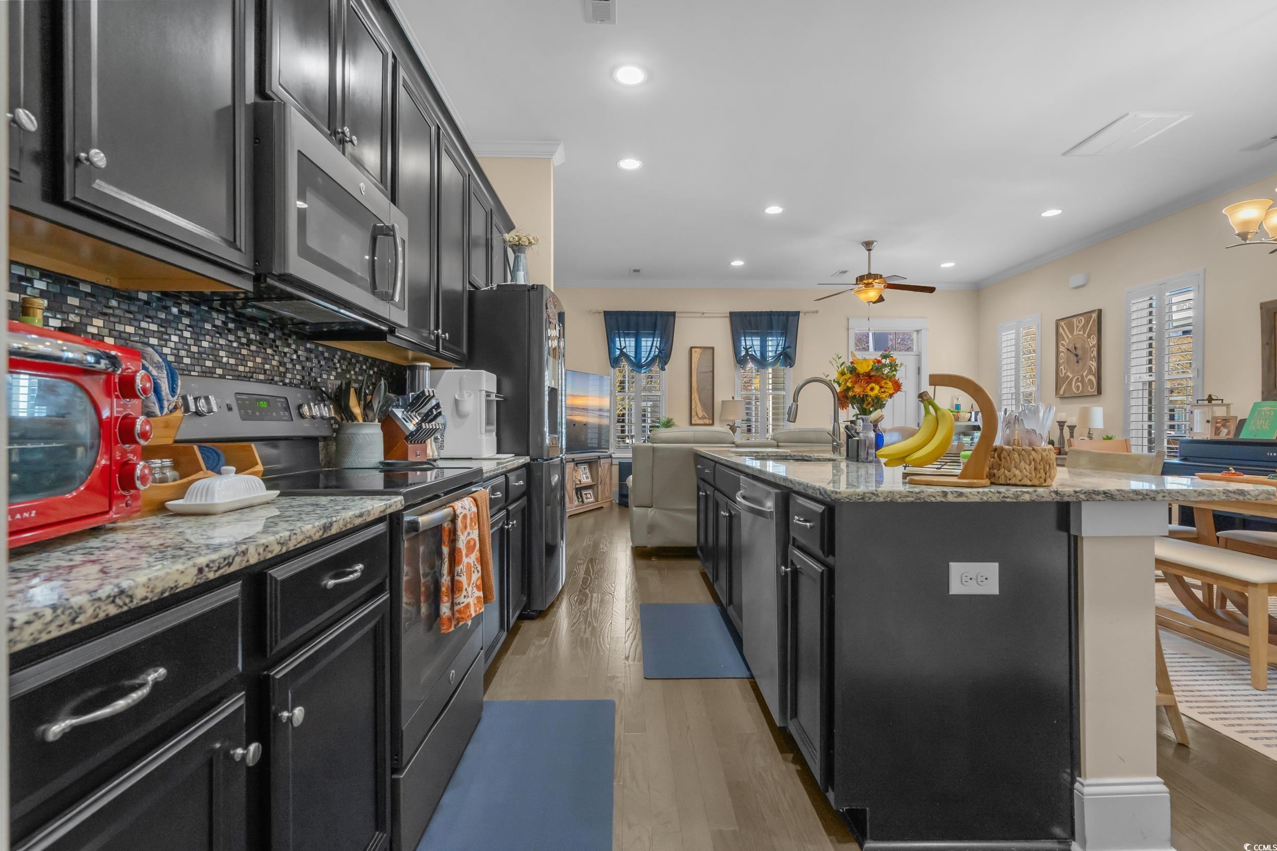 2794E Howard Avenue, Unit A Myrtle Beach, SC 29577 - Photo 37 of 40 Kitchen featuring dark cabinets, open floor plan, appliances with stainless steel finishes, light wood-style floors, and ornamental molding
