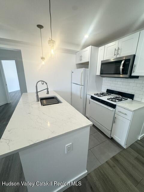 473 Main Street, Unit 1 Catskill, NY 12414 - Photo 3 of 8 a kitchen with stainless steel appliances a refrigerator a stove a microwave and white cabinets