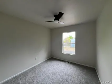 an empty room with a window and a ceiling fan