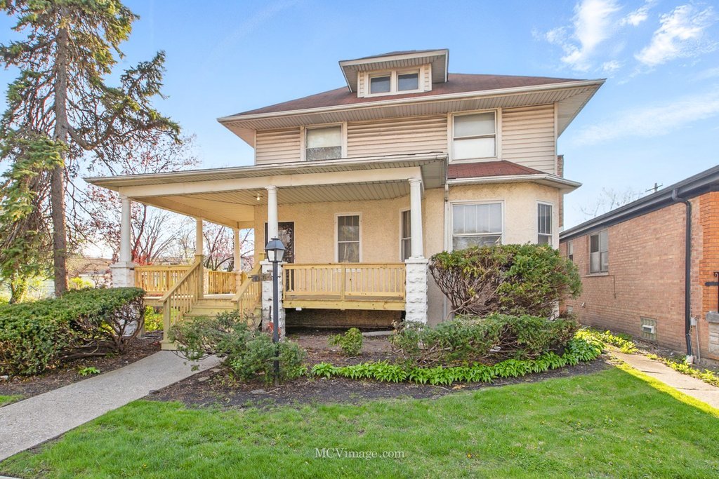 a view of a white house next to a yard with plants and trees