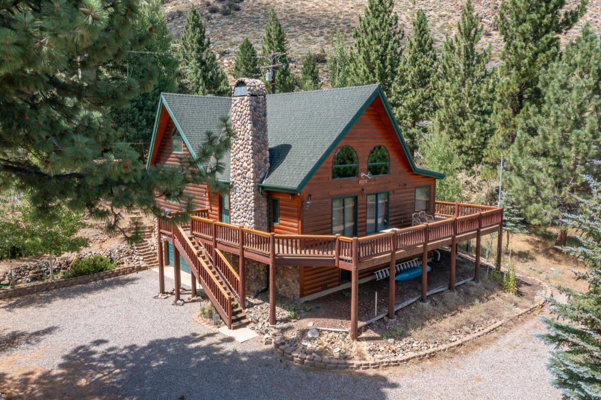 Back of property with a chimney, a wooden deck, a shingled roof, and stairway