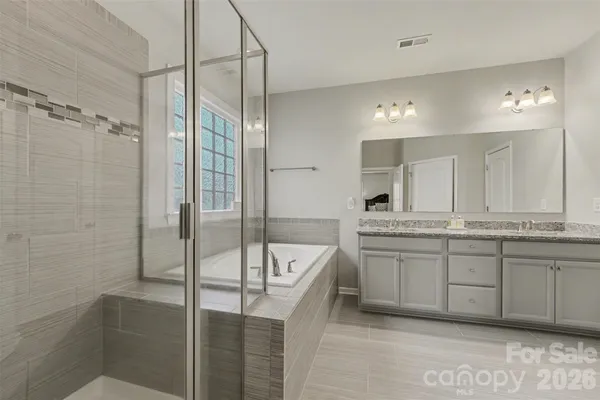 a bathroom with a granite countertop tub sink shower and mirror