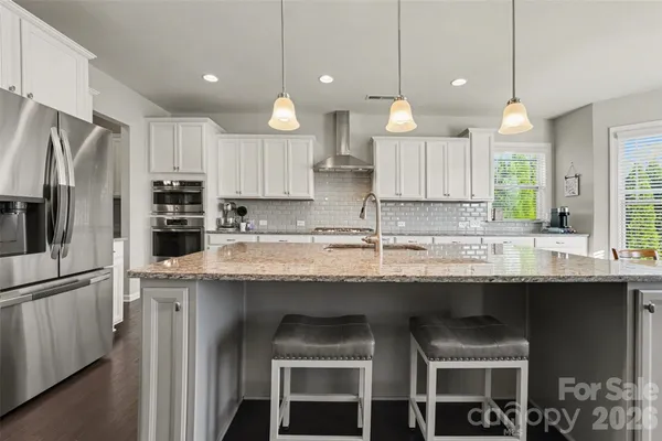 a kitchen with stainless steel appliances granite countertop a sink a stove a refrigerator and island