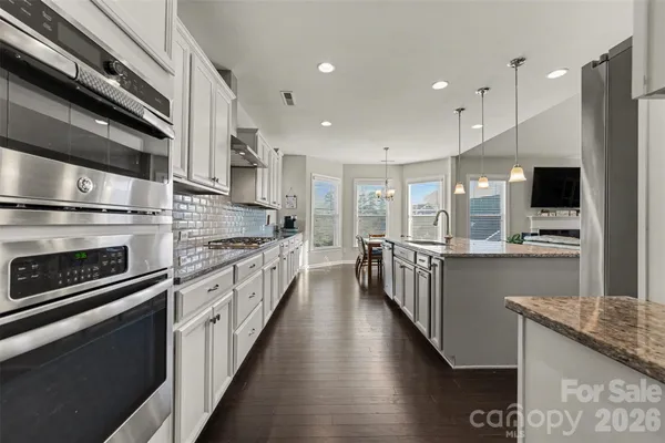 a kitchen with stainless steel appliances kitchen island granite countertop a stove a sink and a refrigerator