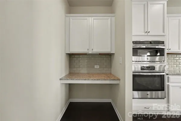 a kitchen with granite countertop white cabinets and stainless steel appliances