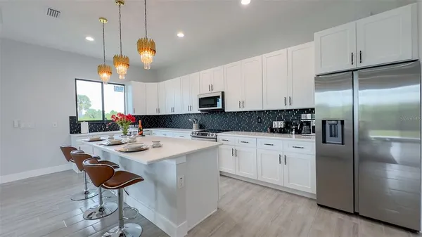 a kitchen with stainless steel appliances granite countertop a sink a stove a refrigerator and island with wooden floor