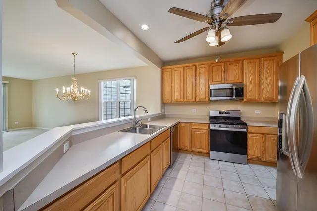 a kitchen with kitchen island granite countertop stainless steel appliances a sink a stove cabinets and a chandelier