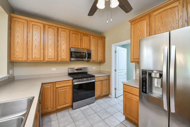 a kitchen with stainless steel appliances granite countertop a refrigerator a stove and a sink with cabinets
