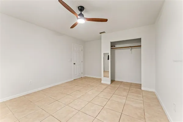 an empty room with white walls and ceiling fan